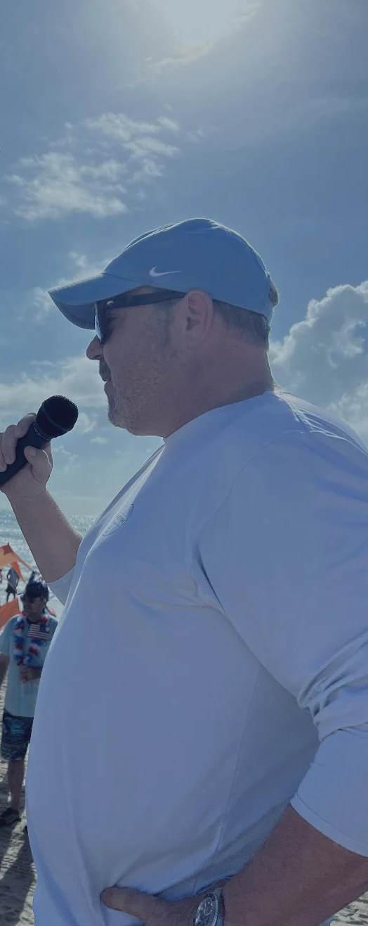 Patrick McNulty speaking into a microphone on the beach at South Padre Island.